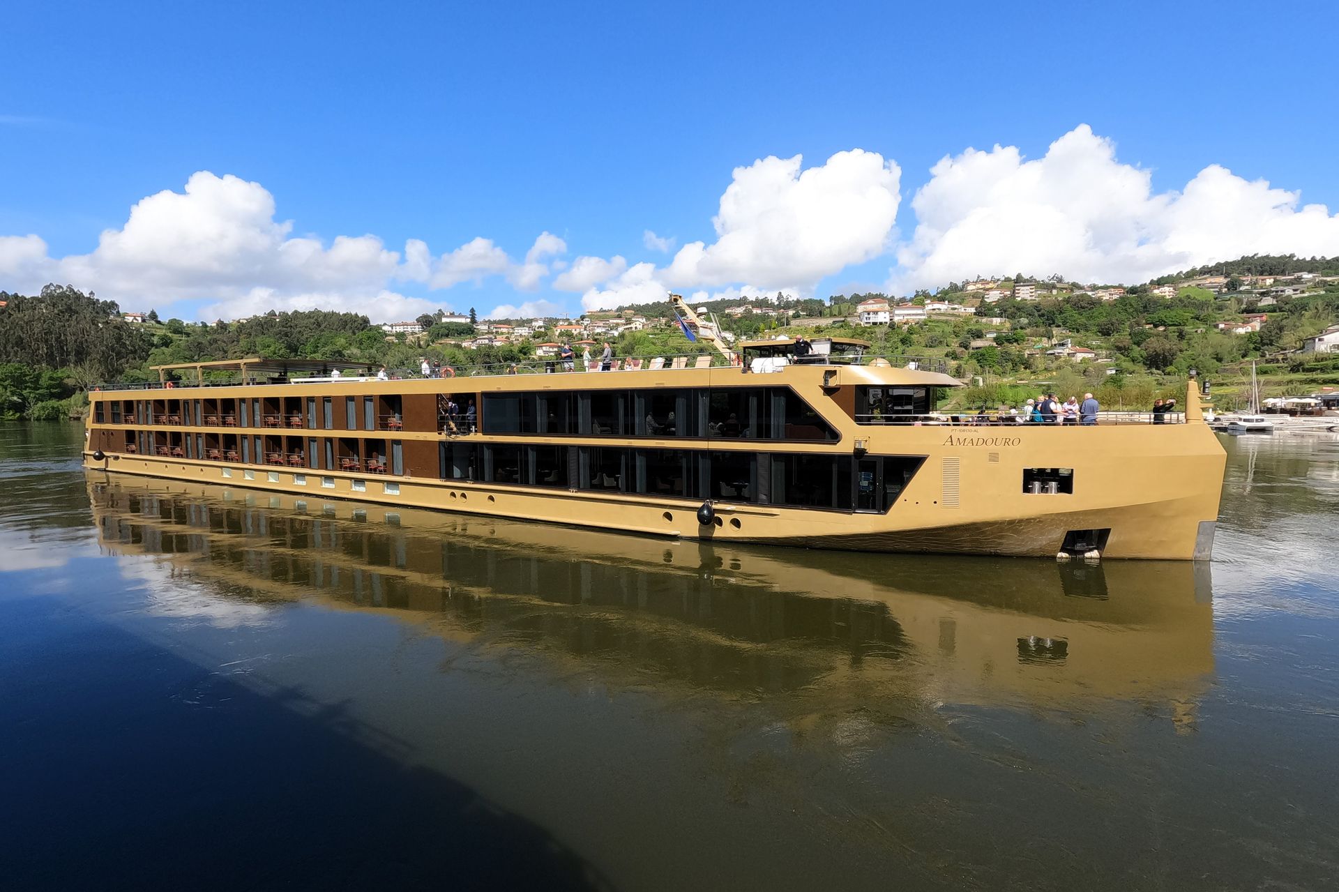The AmaWaterways ship Amadouro on the Douro river, terraced hills behind it.